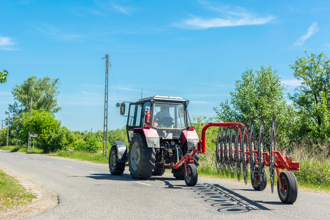 Tractor with a hay tedder on the road