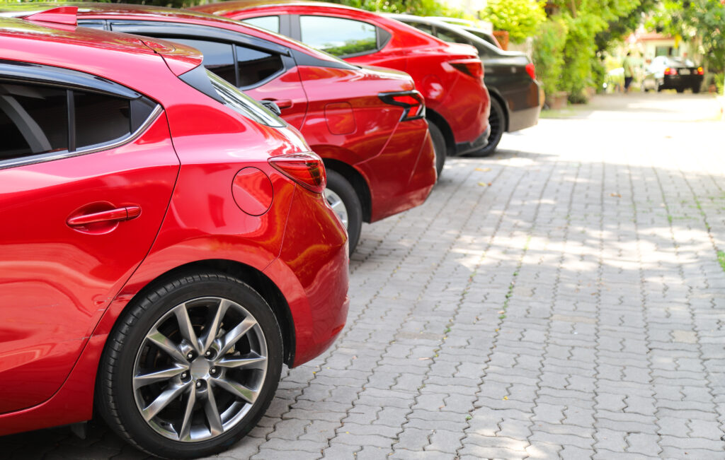a row of red cars parked on the side of a road