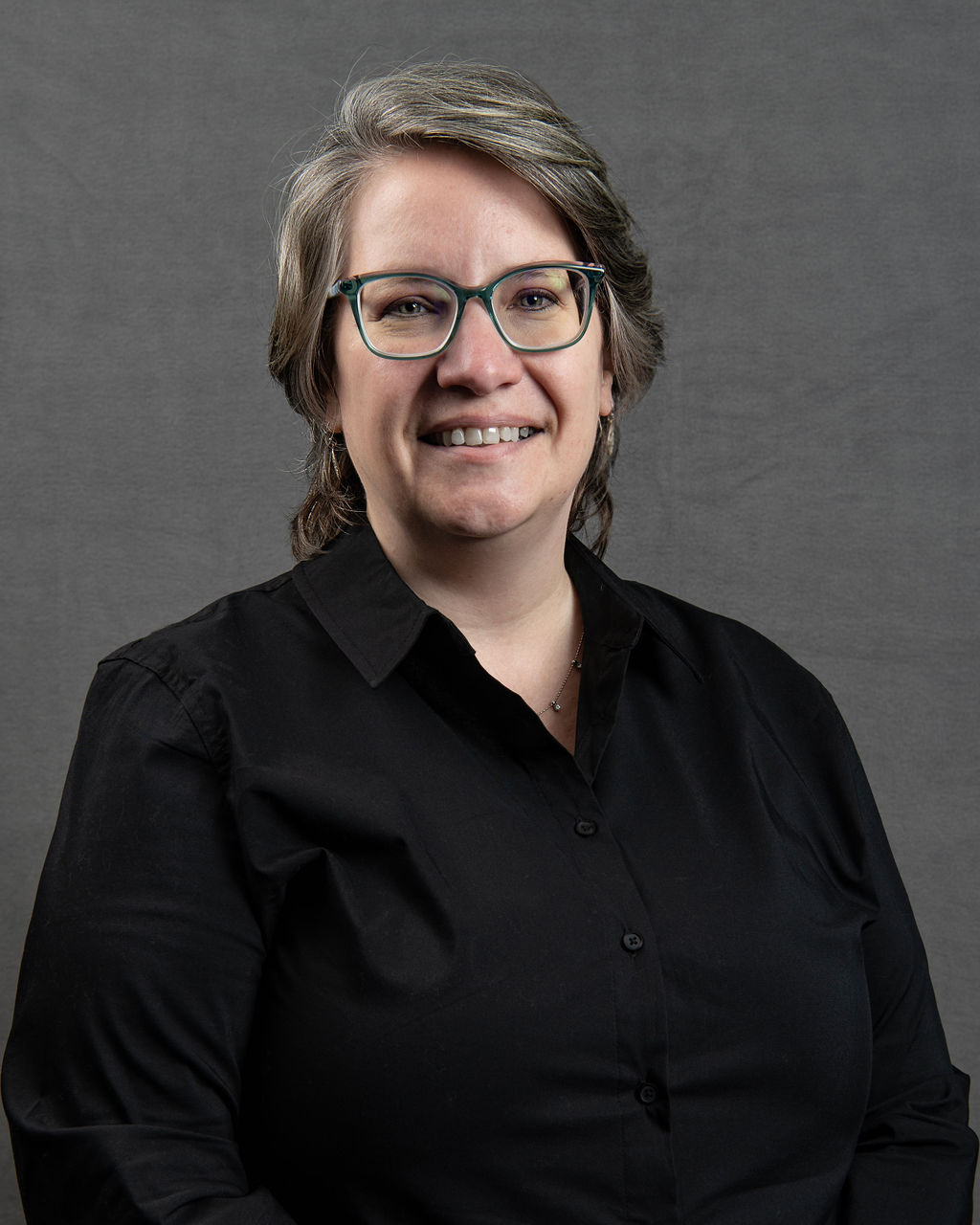 a woman with glasses is smiling for the camera