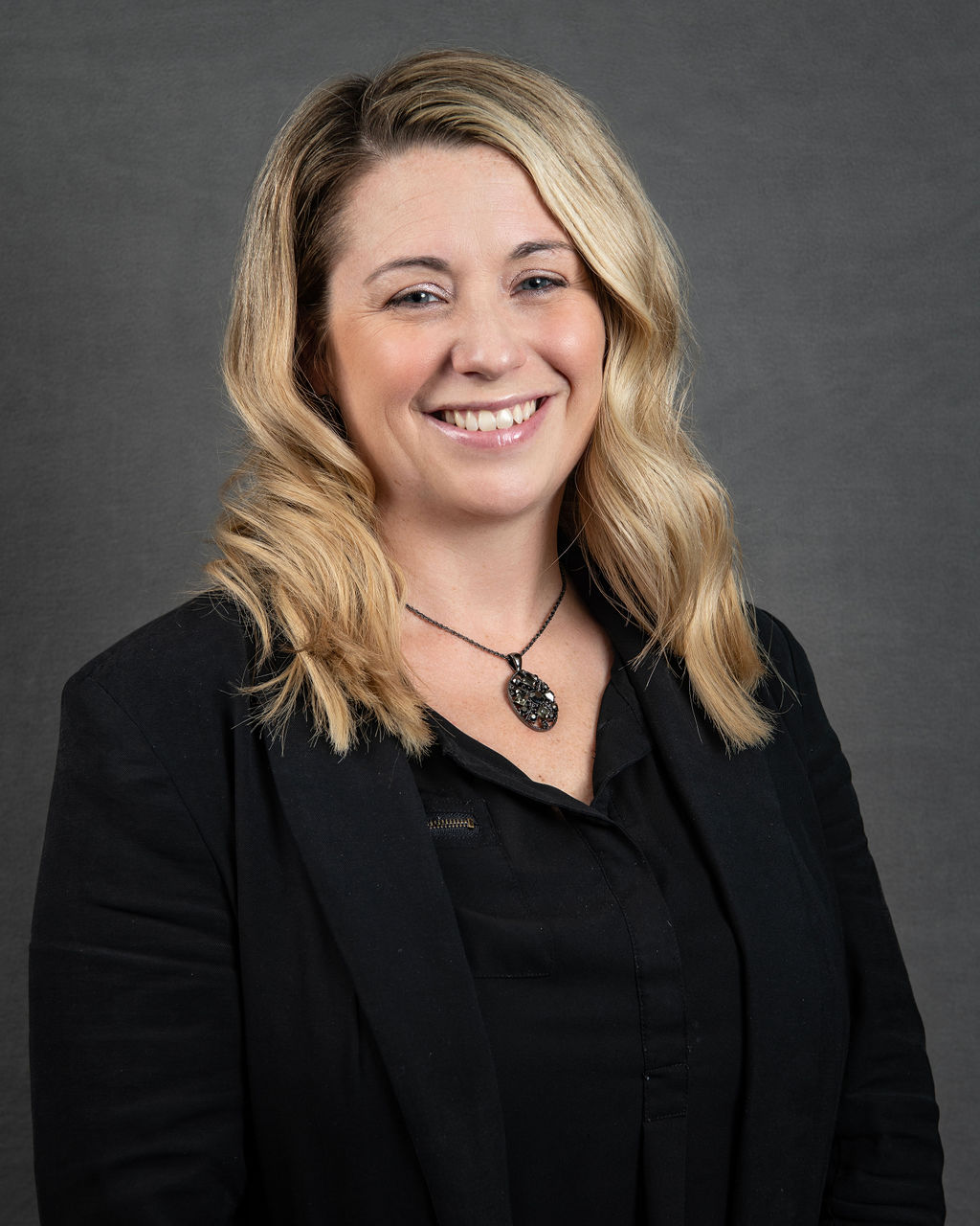 a woman with blonde hair and black shirt smiling