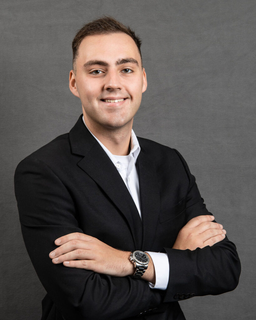 a man in a black suit and white shirt with his arms crossed
