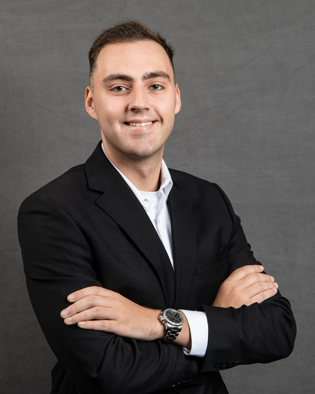a man in a black suit and white shirt with his arms crossed