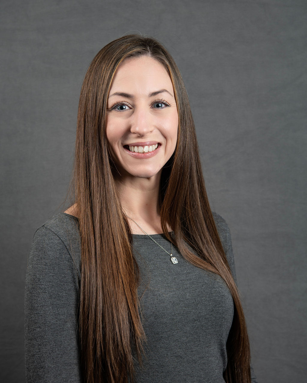 a woman with long brown hair smiling at the camera