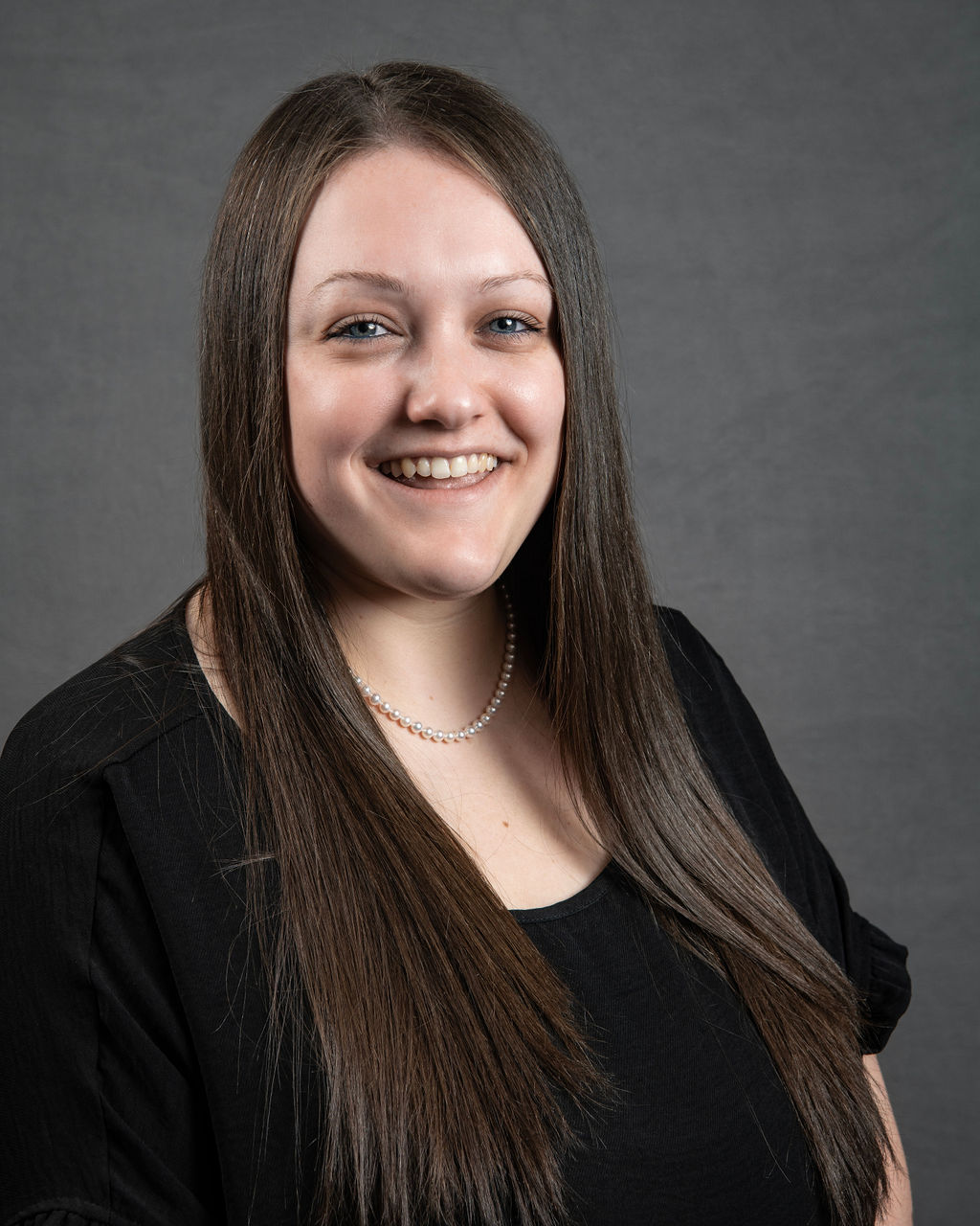 a woman with long brown hair smiling at the camera