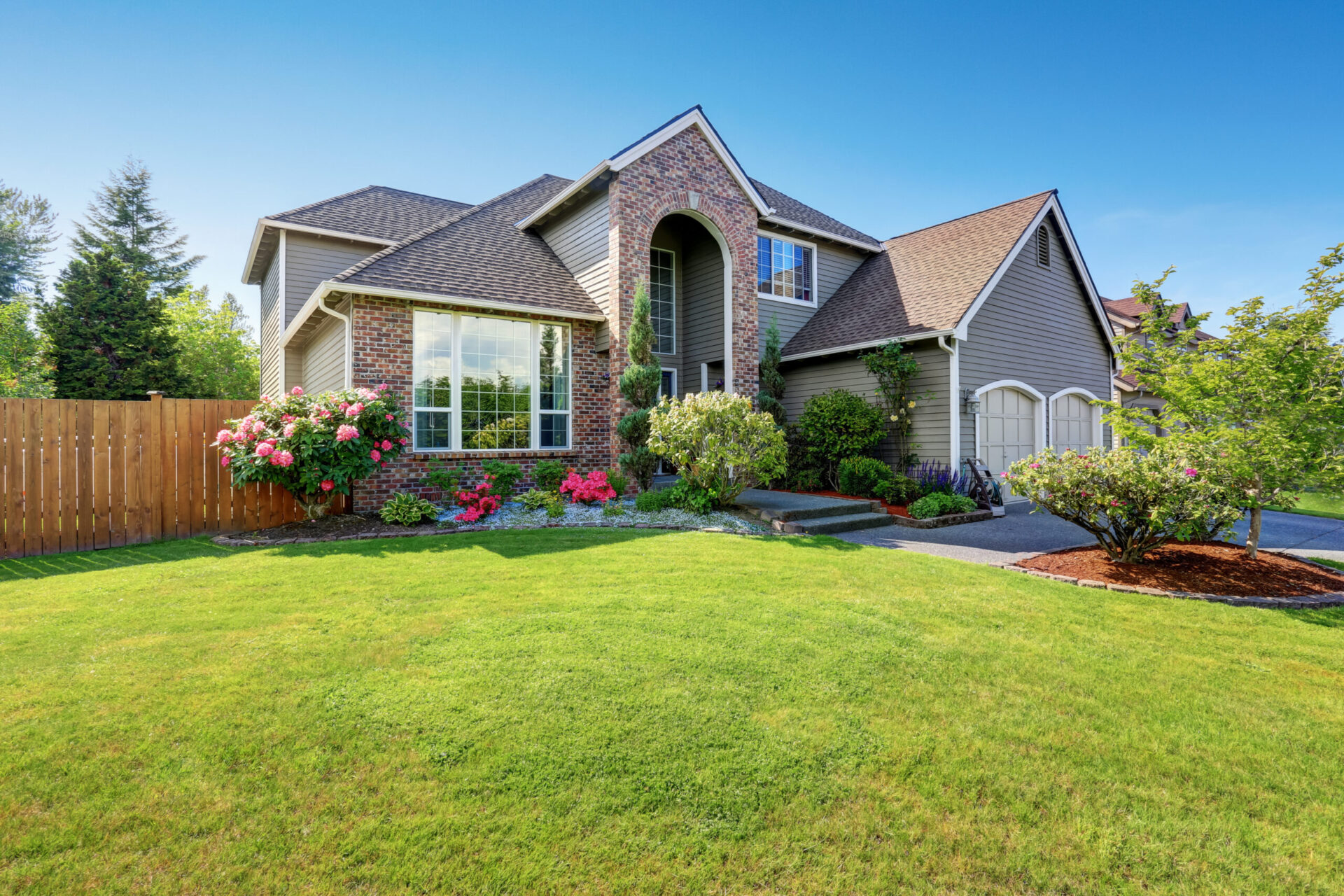 a house with a large yard and a fence in front of it
