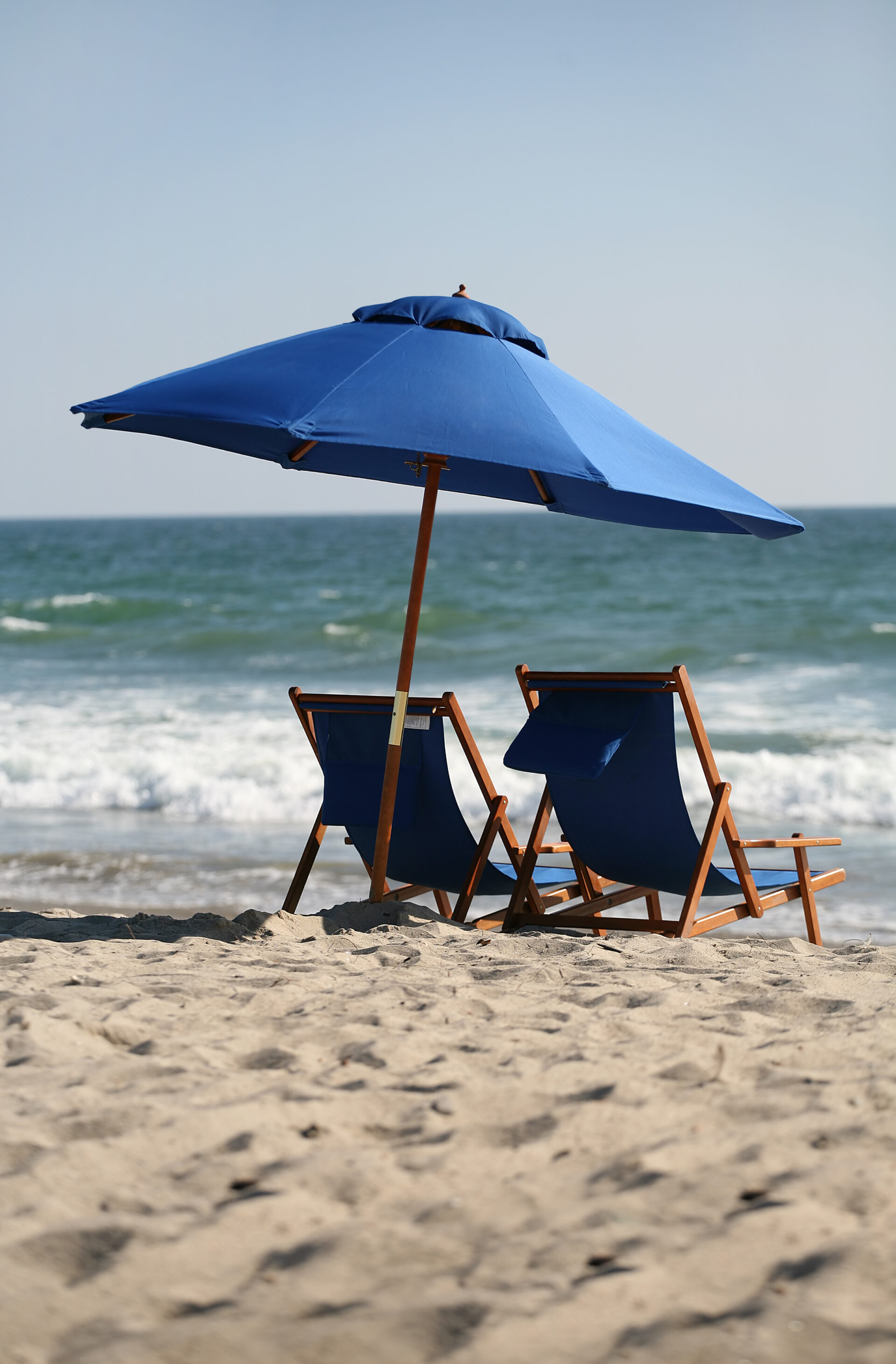 a couple of lawn chairs sitting under an umbrella on a beach