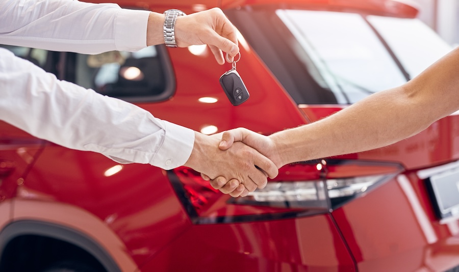 handing over keys over a handshake in front of vehicle