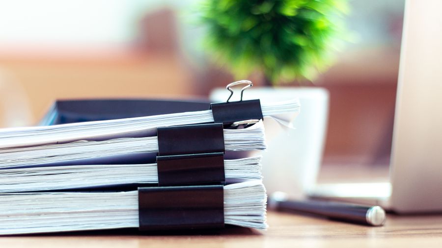 a stack of papers next to a laptop computer