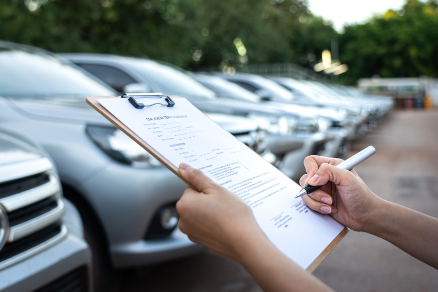 Person holding a clipboard next to row of cars