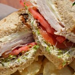 turkey and cheese sandwich with sprouts and chips