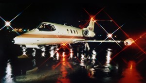 private jet parked on runway at night with lights on