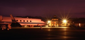 private jet parked in front of airport lit up at night