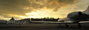 sun setting over airport with partial view of parked plane