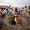 group of kids around bonfire with sticks roasting marshmallows