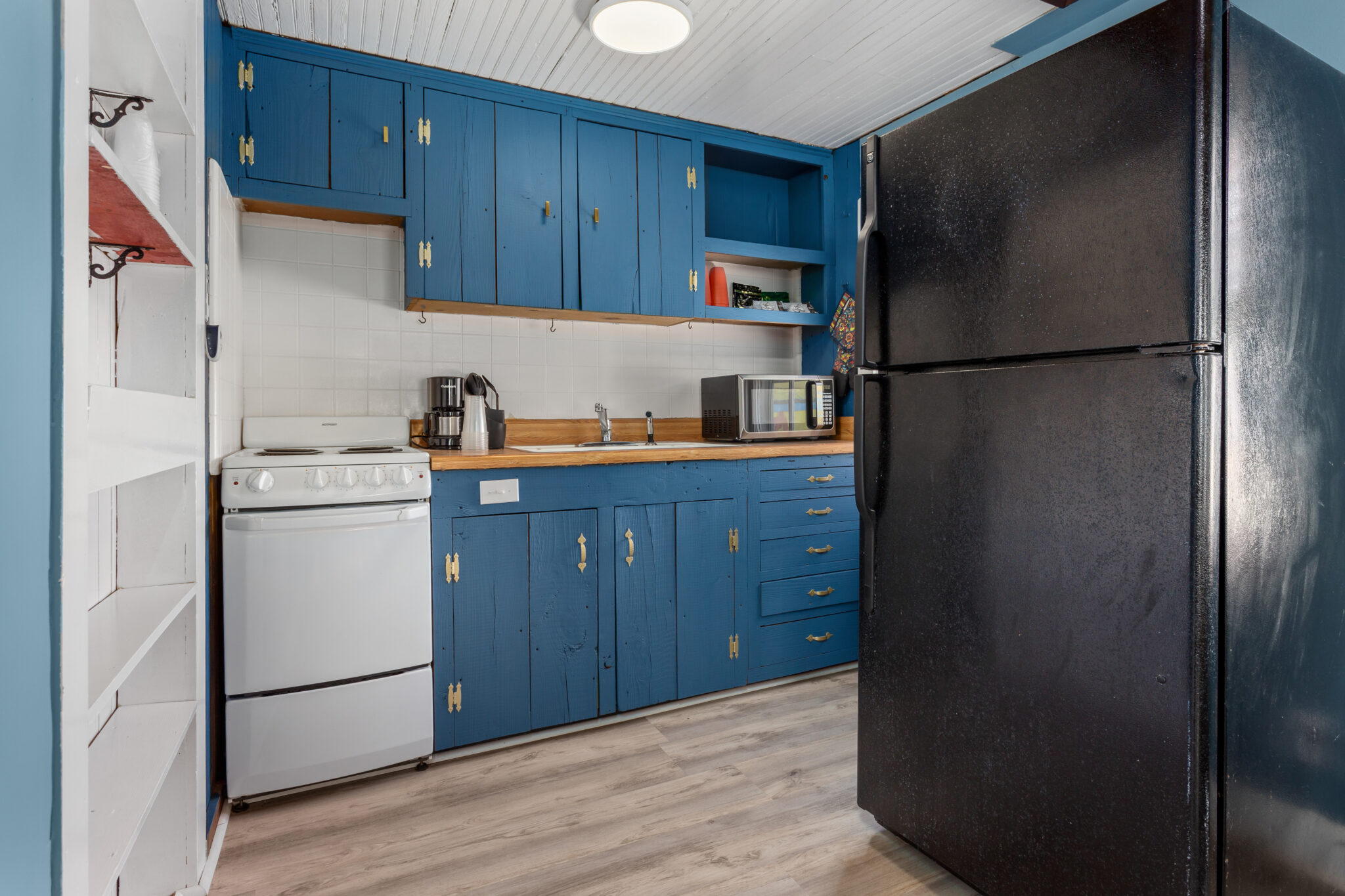 A kitchen with blue cabinets and white appliances