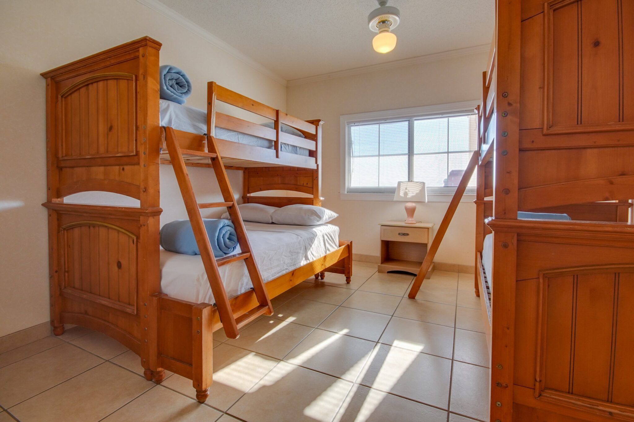 A room with two sets of bunk beds, a nightstand, and a window.