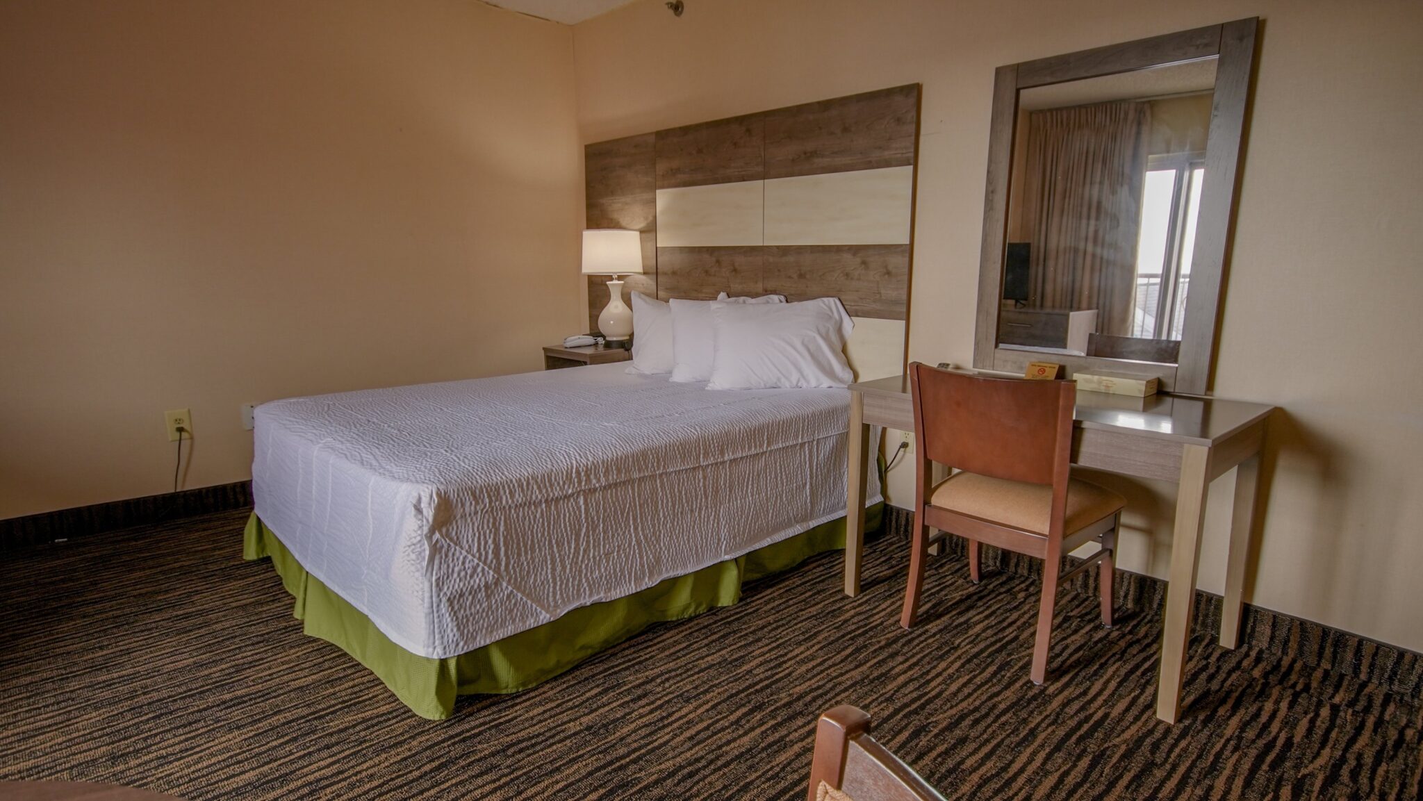 A hotel room with a bed, desk, and chair.