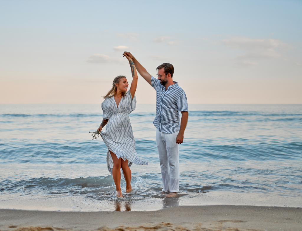 a man and a woman holding hands on the beach