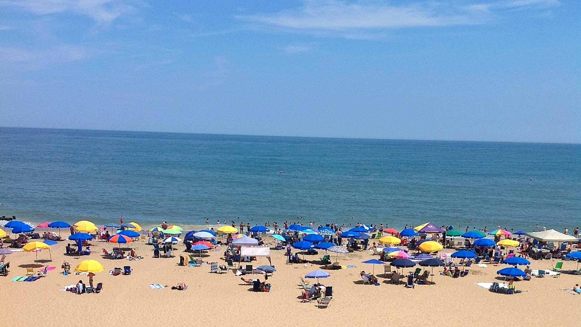 a large group of people on a beach with umbrellas
