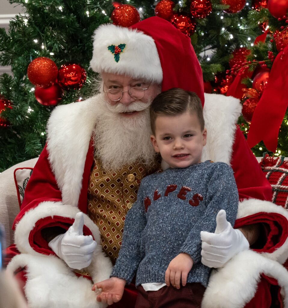 a little boy sitting in a chair next to santa clause