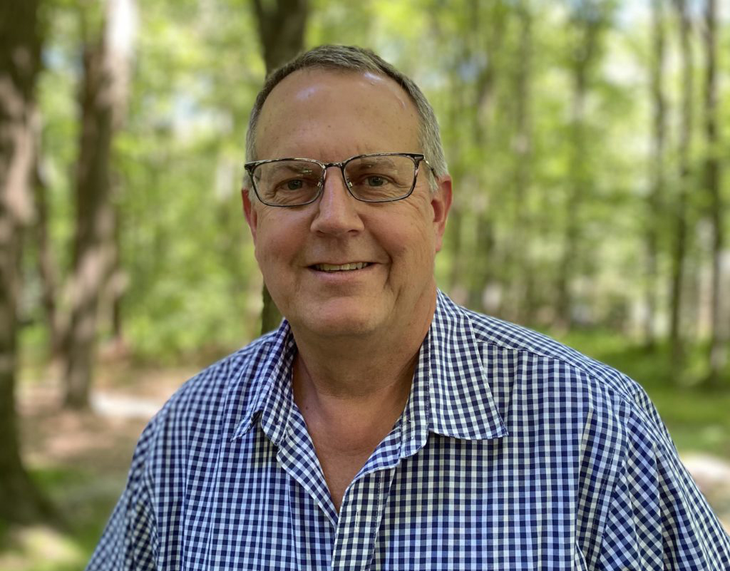 a man standing in the woods wearing glasses