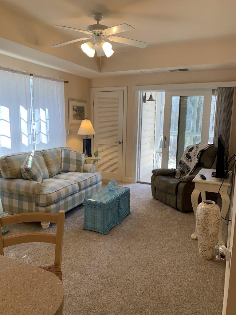 unit living area with love seat, recliner, ceiling fan, and sliding glass door to patio