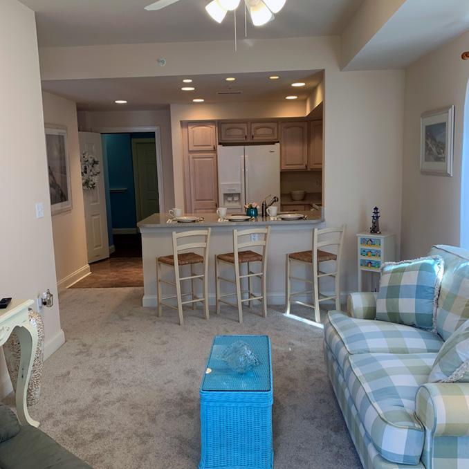 unit 2 living area with love seat, recliner, ceiling fan, and full kitchen in background