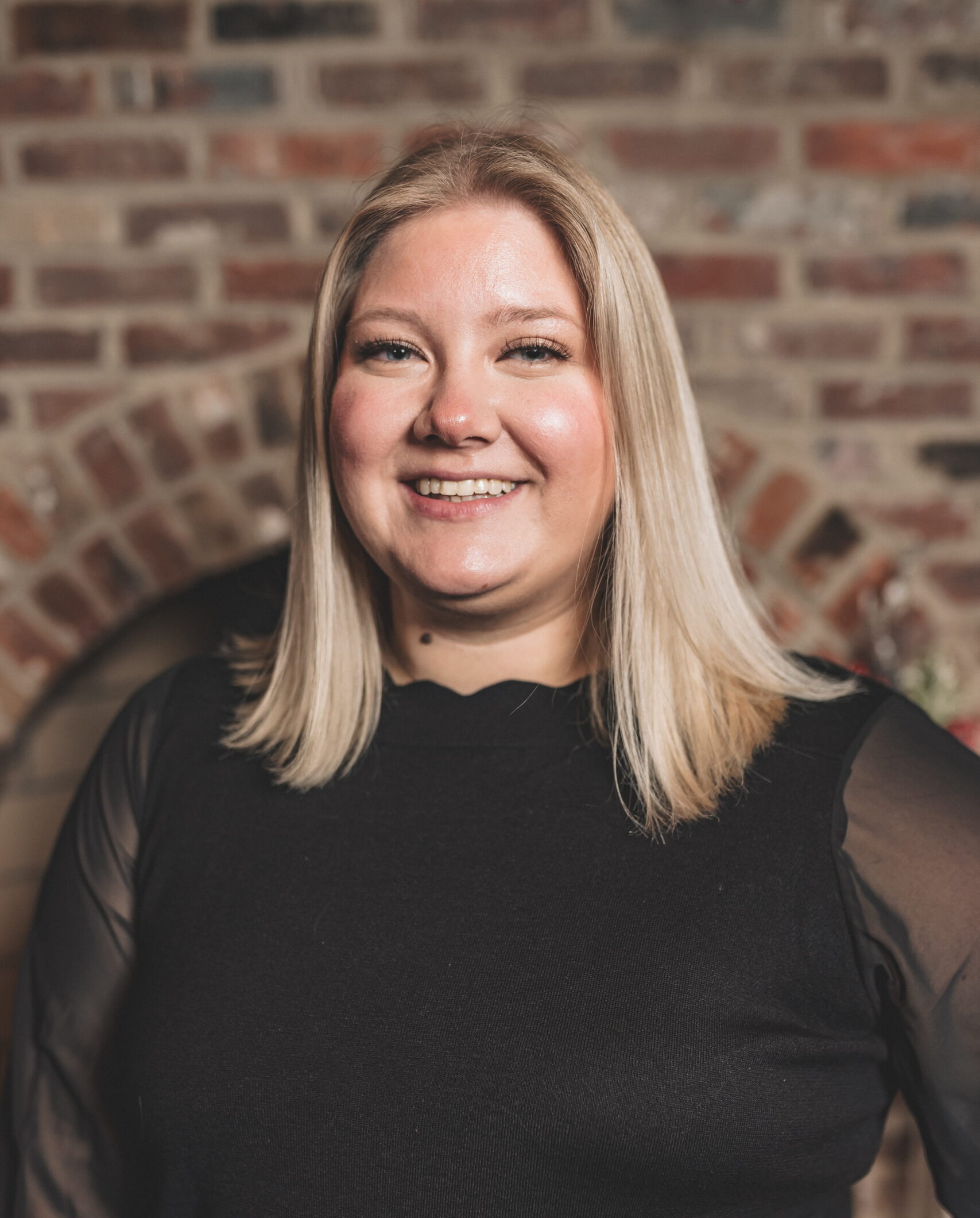 A blonde haired woman wearing a black shirt smiling.