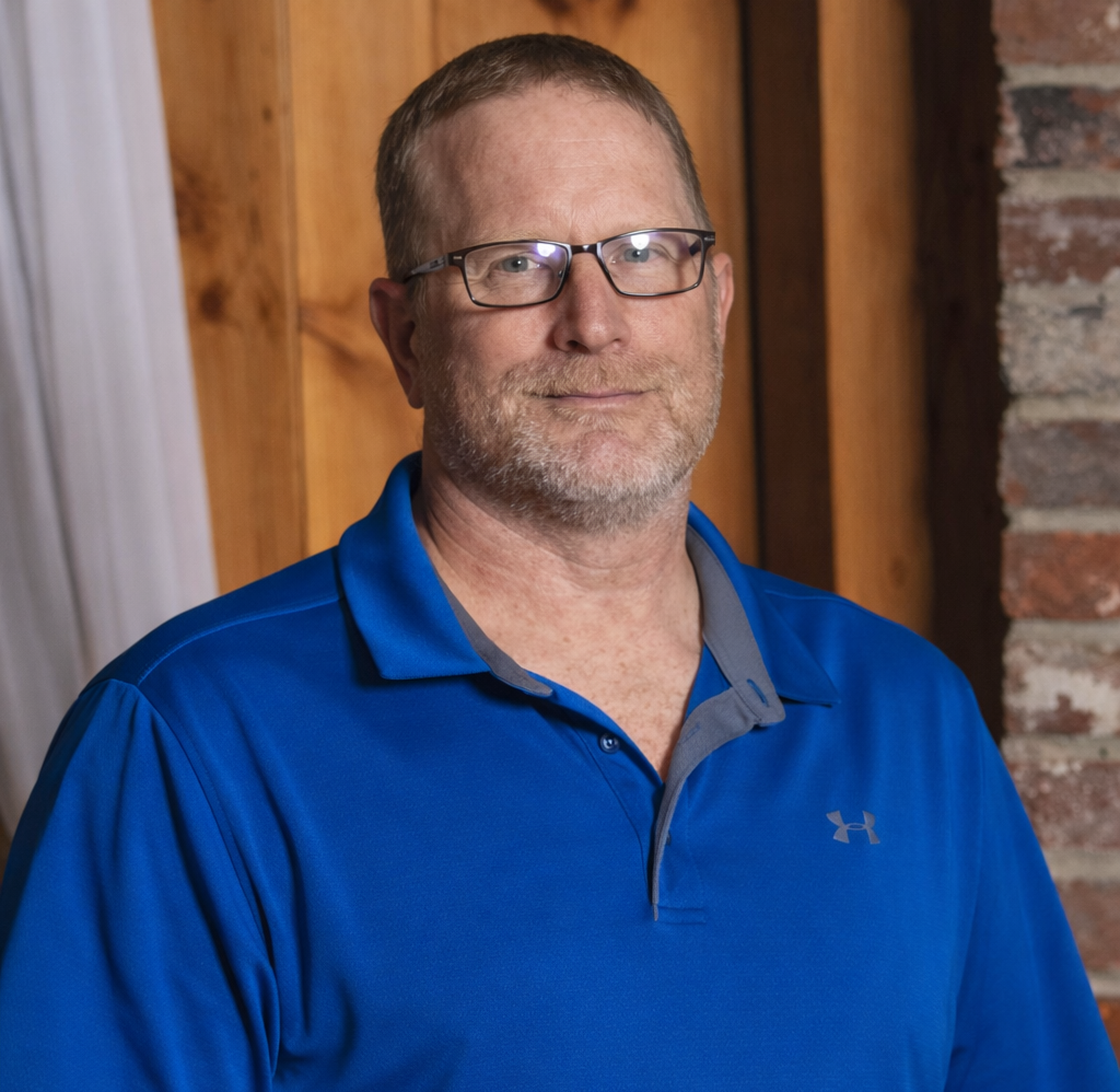A man wearing glasses and a dark blue shirt.