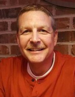 a man in an orange shirt is smiling