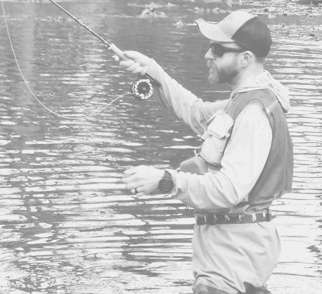 a man standing in the water while holding a fishing rod