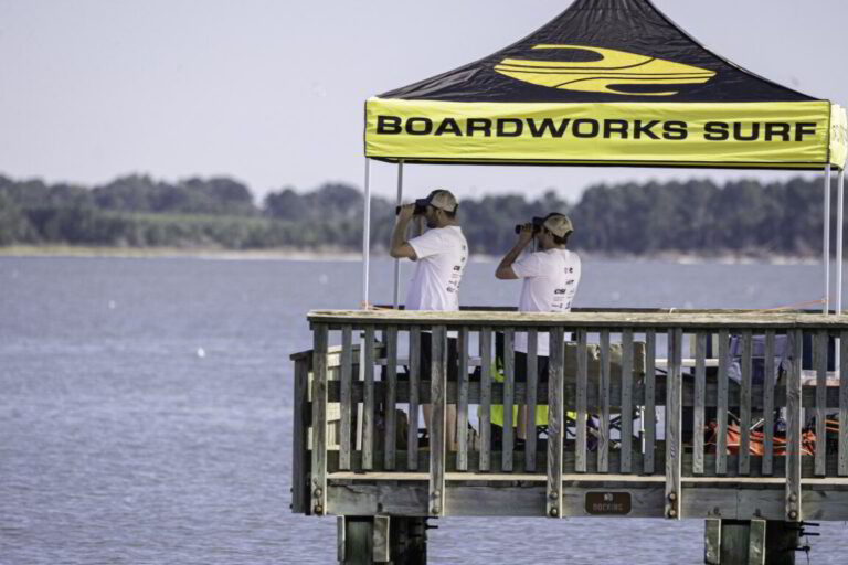 two people standing on a pier with a sign above them