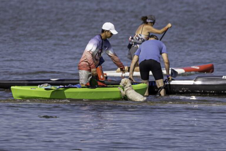 two people and a dog on a green boat