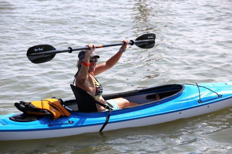 a man in a blue kayak with paddles on the water