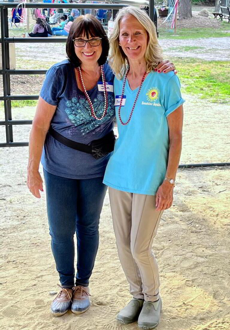 two women standing next to each other in front of a fence