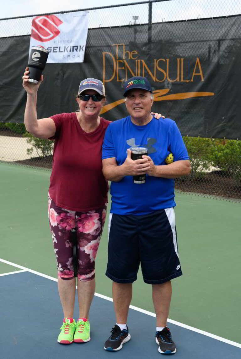 two people standing on a tennis court holding up a trophy