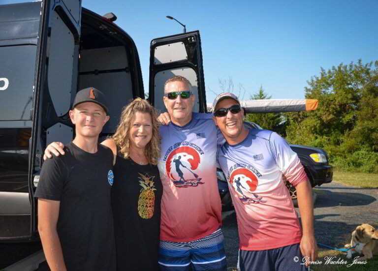 three men and a woman standing in front of a bus