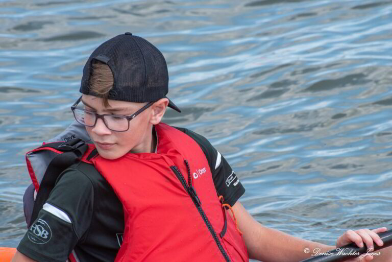 a boy in a life jacket paddling a boat