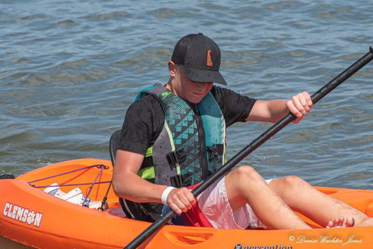 a man in an orange kayak paddling on the water
