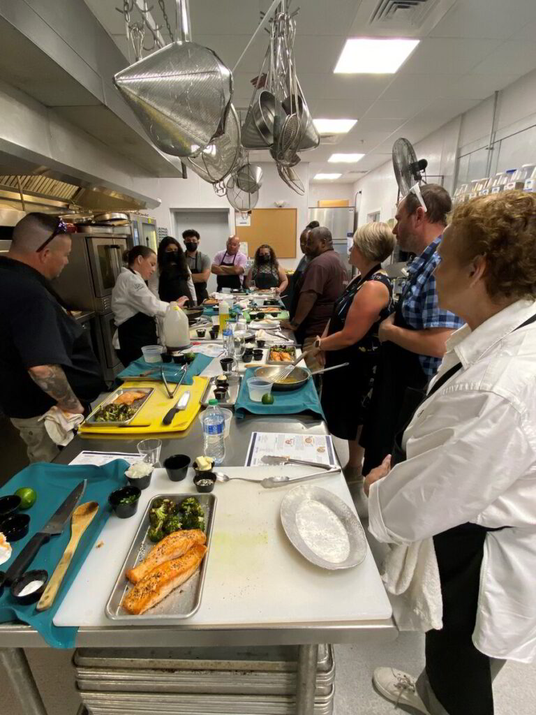 a group of people standing around a kitchen preparing food