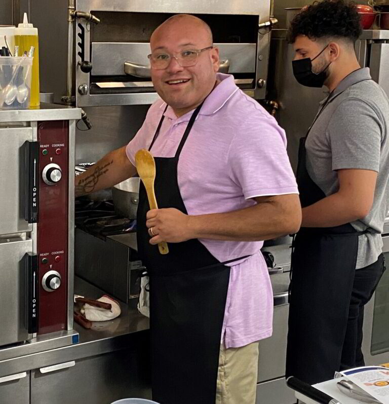 two men in a kitchen preparing food with spatulas