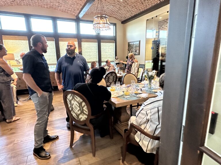 a group of people standing around a dining room table