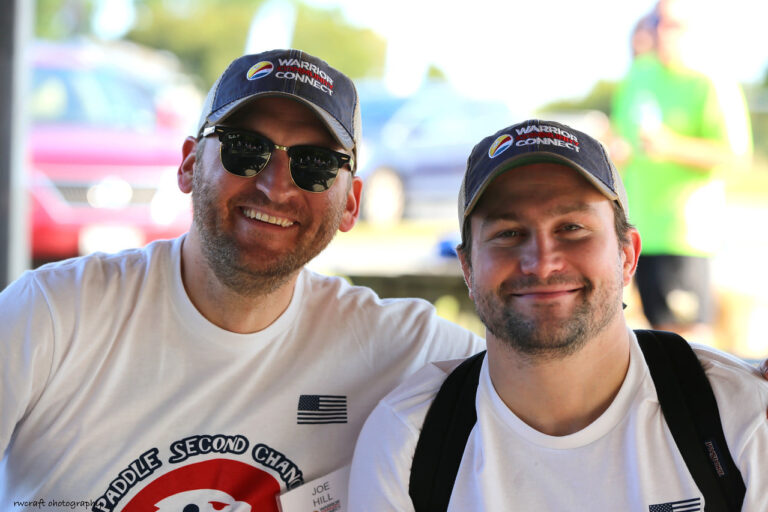 two men wearing hats and sunglasses pose for the camera