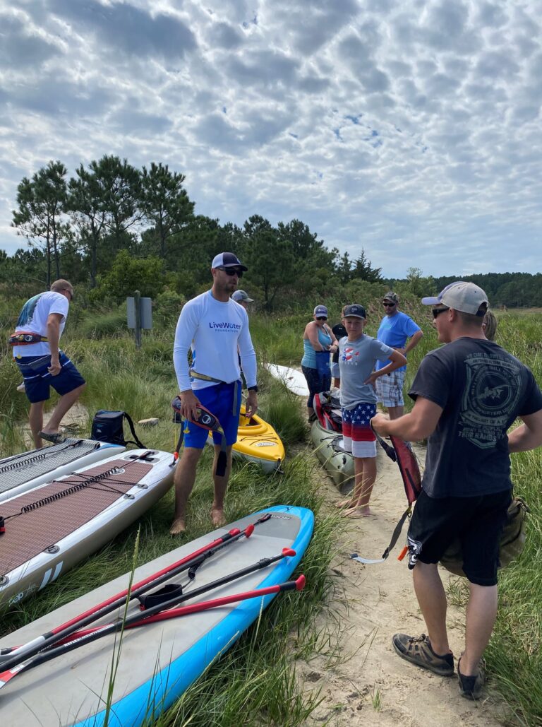 a group of people standing next to some canoes