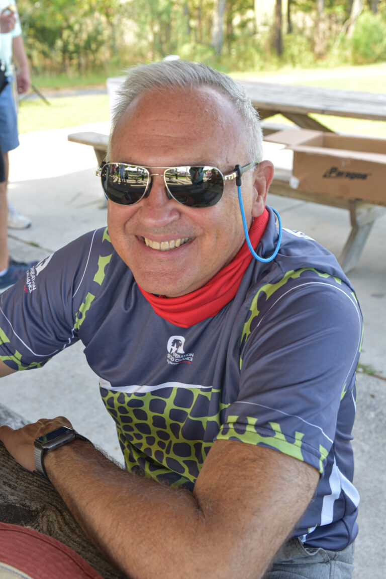 a man with sunglasses on sitting next to a tree