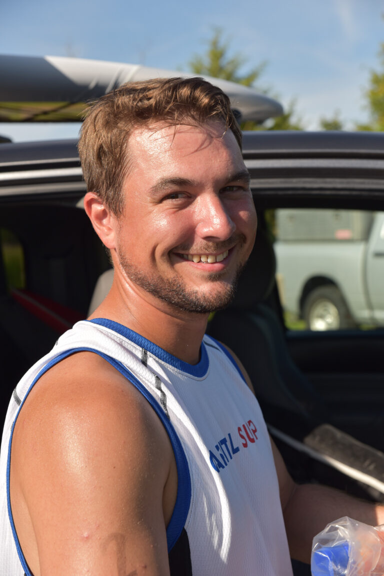 a man in a white tank top holding a plastic bottle
