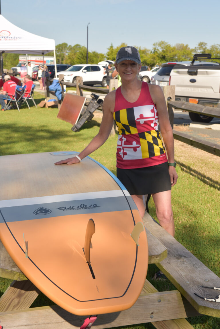 a woman standing next to a surfboard on top of a wooden table