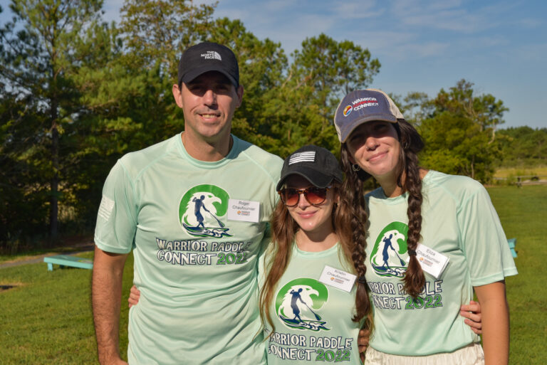 three people in matching shirts and hats posing for a photo