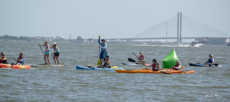 a group of people riding on top of kayaks in the water