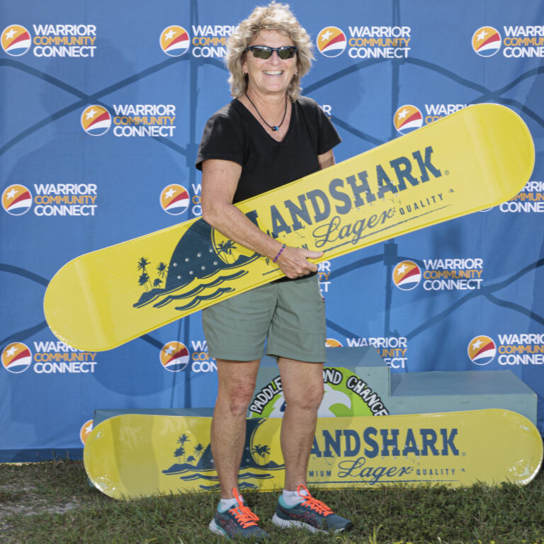 a woman holding a yellow surfboard in front of a blue wall